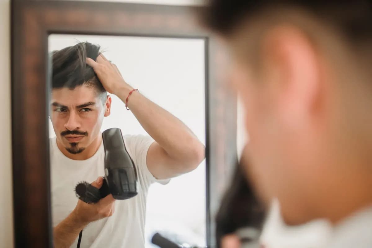 Man examining hair density in bathroom mirror, checking treatment progress after months of treatment