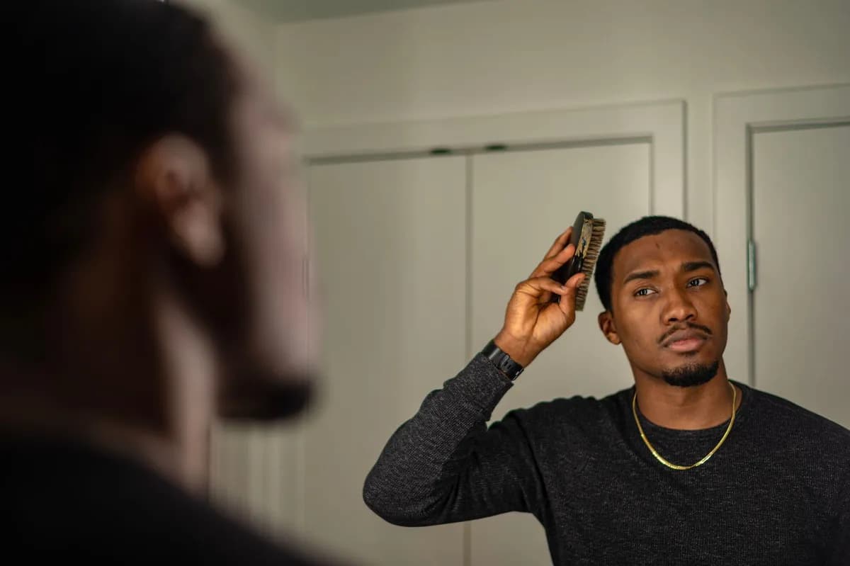 Man examining his hair while looking in the mirror — hair-loss medication Malta hair loss treatment