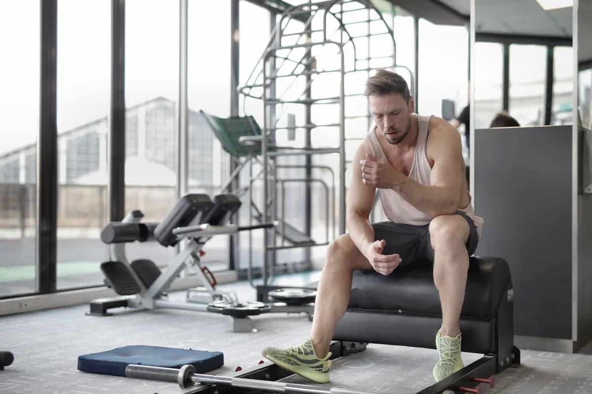 Man resting after a weightlifting workout in a gym — does creatine supplementation affect hair loss?