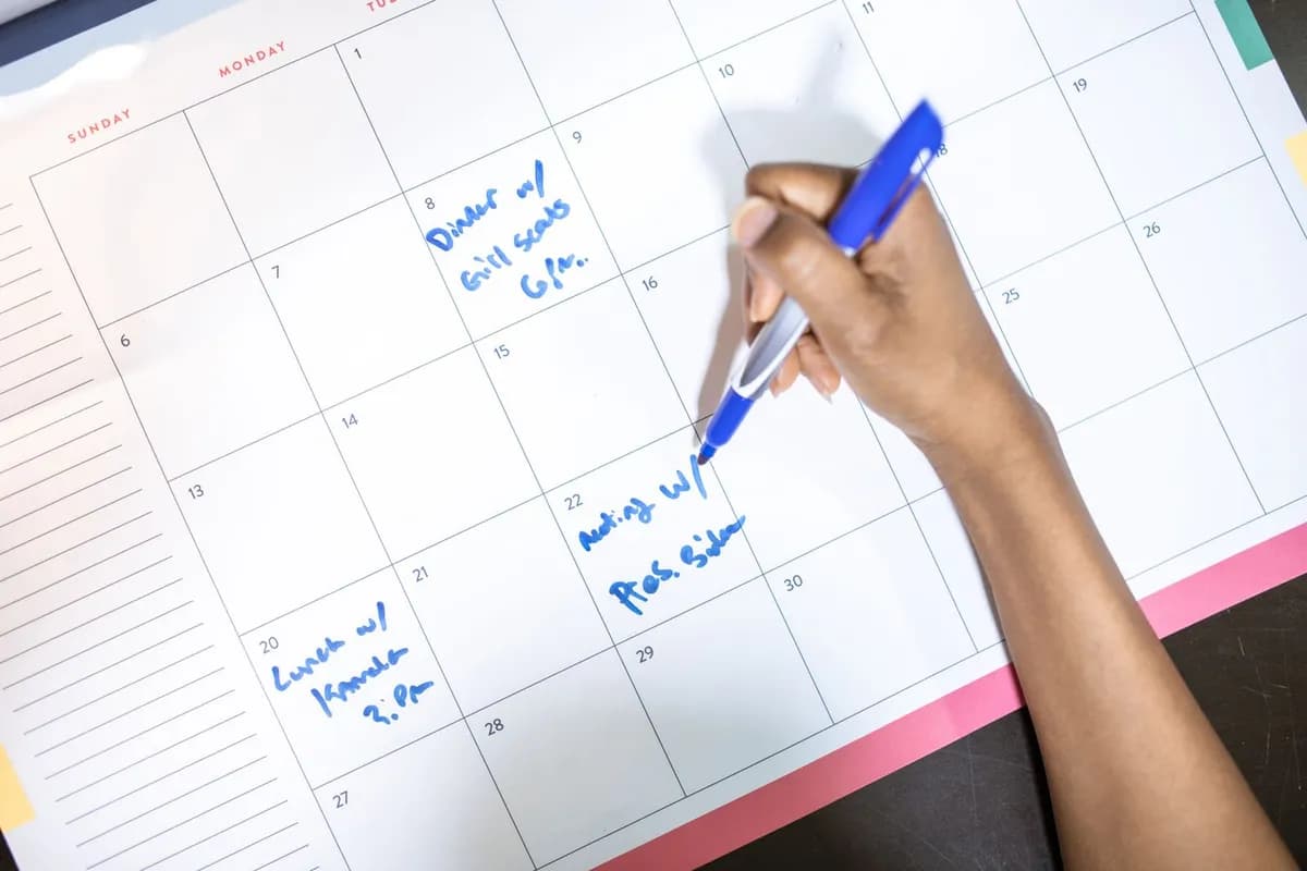 Person writing appointments in a monthly calendar planner, tracking a hair-loss medication schedule
