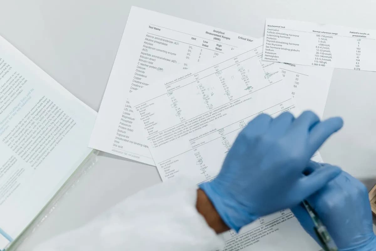 Gloved hands reviewing printed blood test results — understanding lab results for hair loss