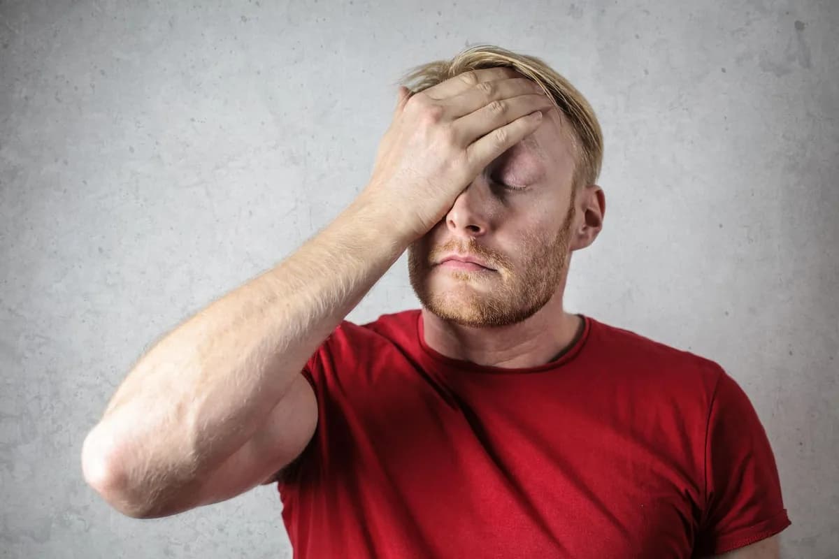Man experiencing hair falling out Malta — stressed and covering his face after noticing sudden hair loss