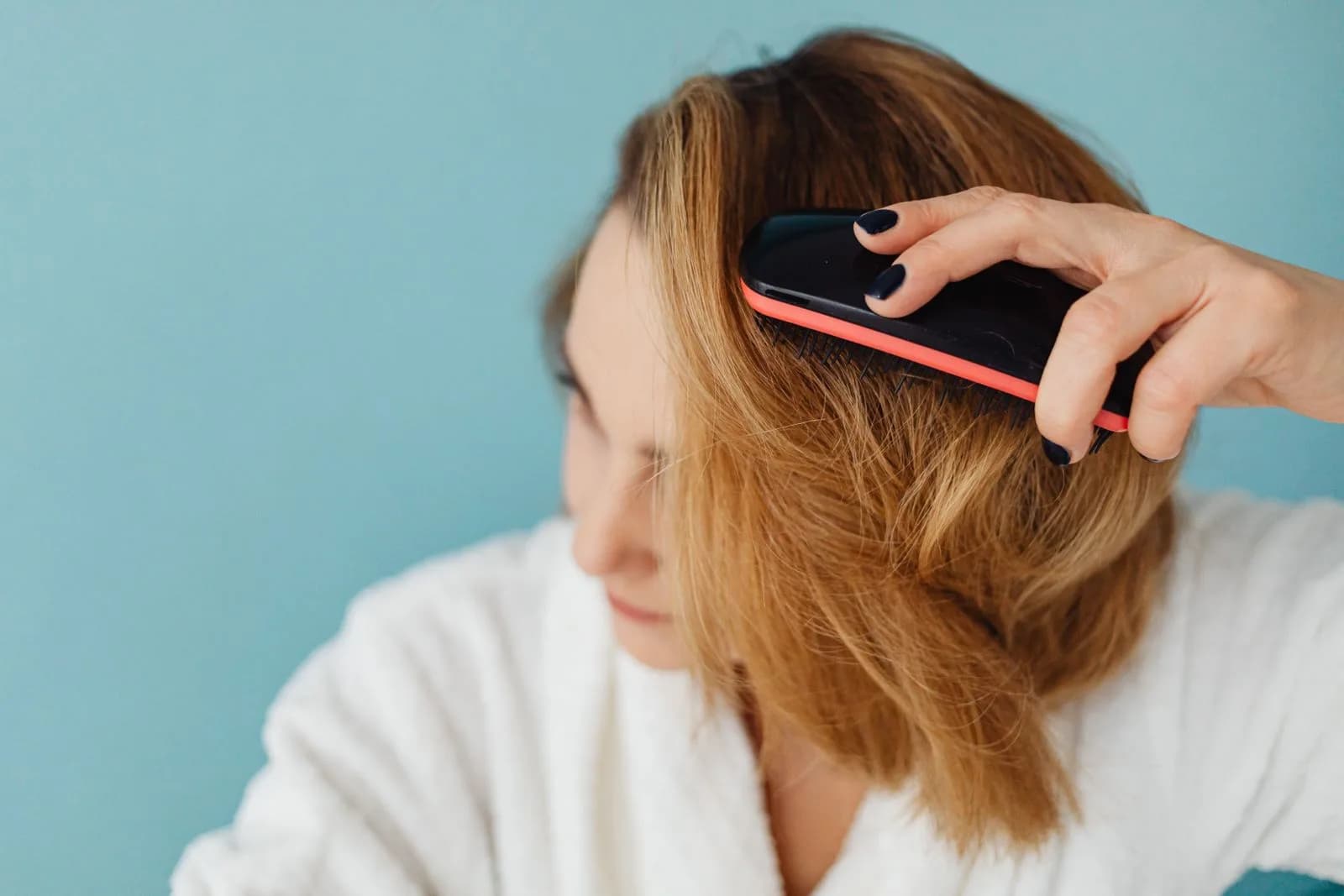 Woman brushing her hair at a bathroom mirror, noticing thinning and shedding