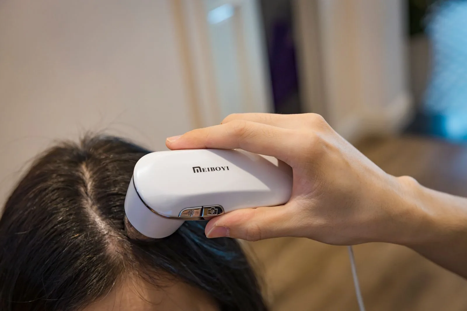 Close-up handheld imaging device examining a person's scalp during assessment