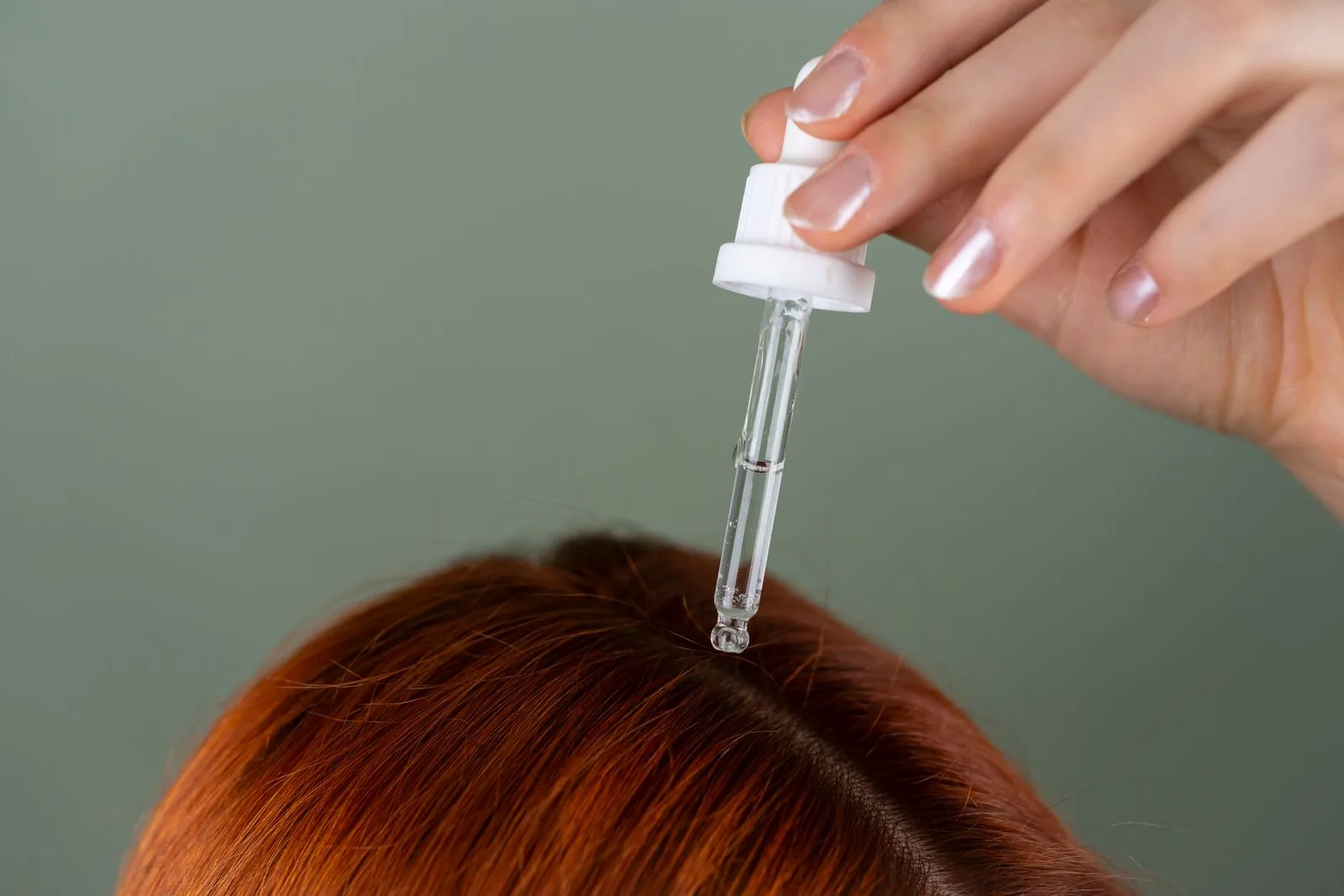 Precision dropper applying a topical hair treatment serum to the scalp